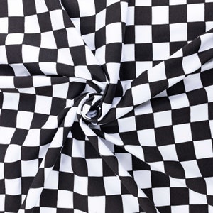 May include: Black and white checkered fabric with a swirling pattern. The fabric is made of a soft, smooth material and has a subtle sheen.