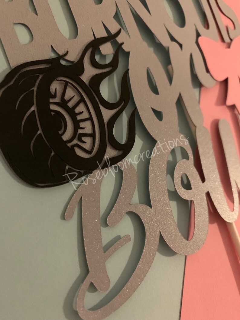 May include: Silver glitter cake topper with the words "Burnout is a B*tch" and a black silhouette of a tire with flames.
