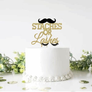 May include: Gold glitter cake topper with the text "Staches or Lashes" and a black mustache and eyelashes.