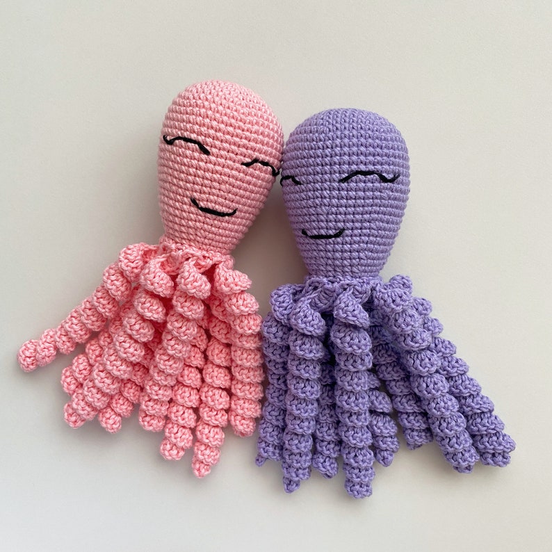 May include: Two crocheted octopus plushies, one pink and one purple, with embroidered smiling faces.