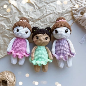 Puede incluir: Tres mu&ntilde;ecas de crochet con vestidos de diferentes colores. Las mu&ntilde;ecas tienen el pelo casta&ntilde;o y caras blancas con ojos negros. Los vestidos son rosa, verde y morado.