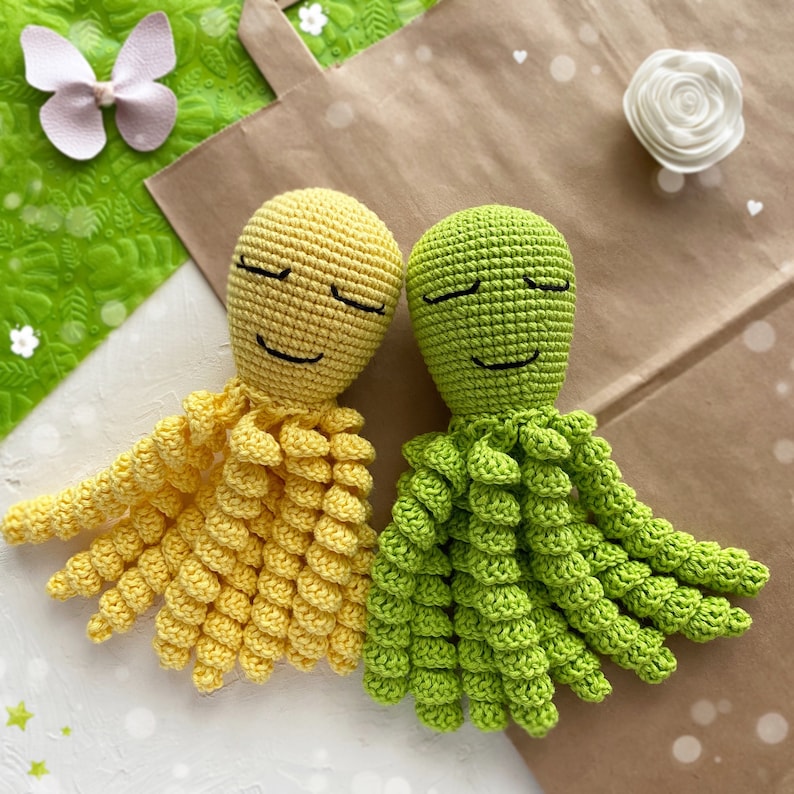 May include: Two crocheted octopus plushies with closed eyes. One is yellow and the other is green.