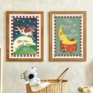 May include: Two framed nursery art prints. One features a cow jumping over the moon with text. The other shows a moon with a face playing a drum, with the text "The Man in the Moon". Both are in wooden frames.