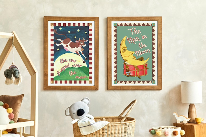 May include: Two framed nursery art prints. One features a cow jumping over the moon with text. The other shows a moon with a face playing a drum, with the text "The Man in the Moon". Both are in wooden frames.