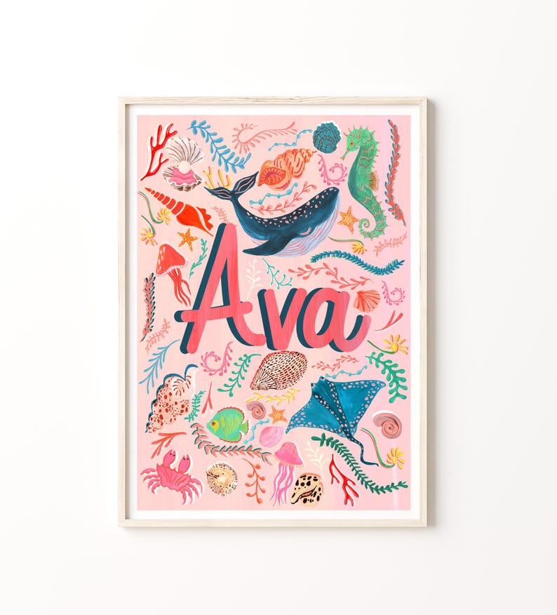 May include: A rectangular wall art print featuring the name Ava in large pink letters centered on a light pink background. The design includes colorful illustrations of a blue whale, a stingray, a green seahorse, a pink crab, and various shells.