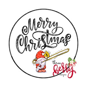 Könnte beinhalten: Rundes Grafikdesign mit schwarzem Rand. Der Text "Merry Christmas" ist in einer Schriftart geschrieben. Ein Zwerg mit roter Mütze und Mantel spielt Posaune. Die Grafik enthält auch den Text "three berry designs" und eine Erdbeerillustration.