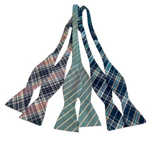 May include: Three bow ties in different plaid patterns. One is blue and white, one is pink and black, and one is green and white.