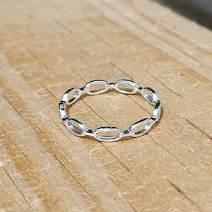 May include: A silver ring with a chain-like design made of oval links.