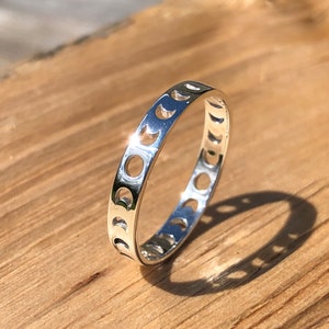 Può includere: Un anello d'argento con un delicato design di lune crescenti tagliate intorno alla fascia.
