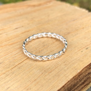May include: A silver braided ring with a simple design.