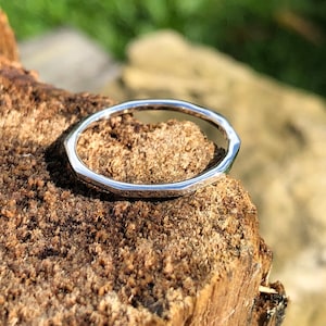 Könnte beinhalten: Ein silberner Ring mit einer strukturierten, facettierten und leicht unregelmäßigen Band.