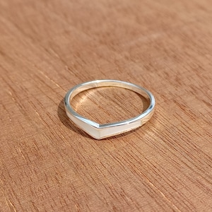 Può includere: Un anello d'argento con un'incisione bianca a forma di V.