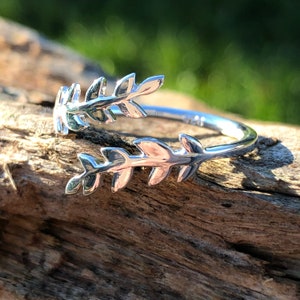 May include: A silver ring featuring a delicate leaf design. The ring is open and adjustable to fit different finger sizes.