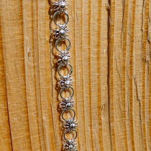 Puede incluir: Un collar de cadena de plata con un delicado diseño de flores. Cada eslabón es un círculo pequeño abierto con una forma de flor en el centro.