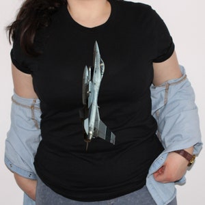 May include: A black t-shirt with a grey and white fighter jet graphic printed on the front.