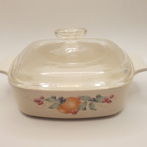 May include: A white ceramic baking dish with a glass lid. The dish has a floral design with fruit and berries.