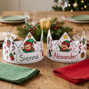 May include: Two white paper crowns featuring colorful illustrations of elves, gift boxes, and candy canes. One crown displays the name Sienna in black text, and the other displays the name Alexander in red text, both centered on the front.