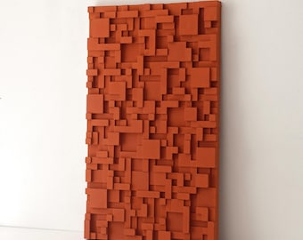 May include: A rectangular, terracotta-colored wall art piece with a geometric, three-dimensional design. The artwork features a repeating pattern of varying-sized, raised rectangular blocks, creating a textured surface. The piece is mounted on a white wall.