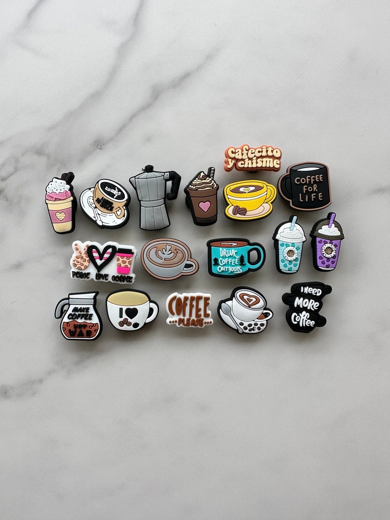 Op de afbeelding: Een verzameling van 15 kleurrijke koffie-charms met verschillende ontwerpen, waaronder koffiekopjes, mokken, koffiebonen en zinnen zoals "Coffee for Life" en "Ik hou van koffie".