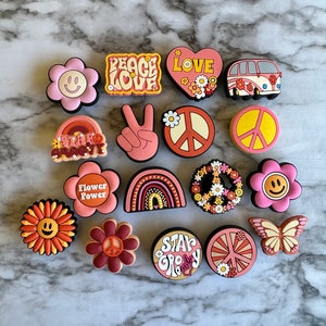 May include: A set of 15 colorful, retro-themed charms featuring peace signs, flowers, rainbows, and the words "Peace Love", "Flower Power", "Stay Groovy", and "Love".