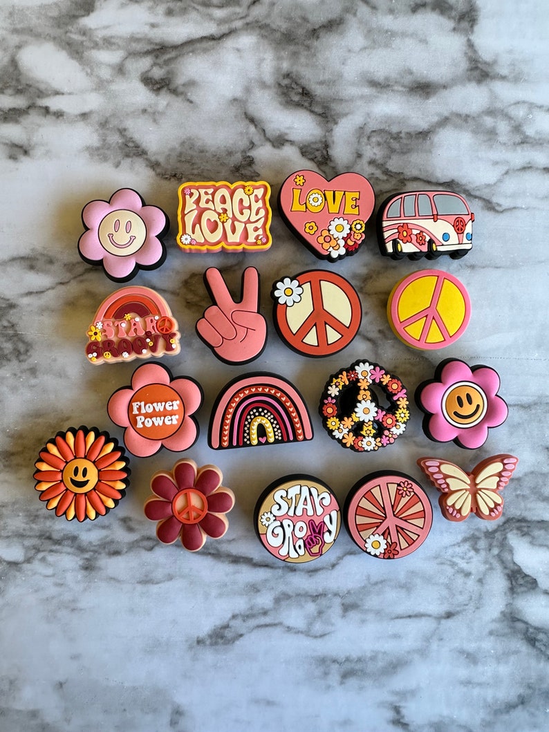 May include: A set of 15 colorful, retro-themed charms featuring peace signs, flowers, rainbows, and the words "Peace Love", "Flower Power", "Stay Groovy", and "Love".