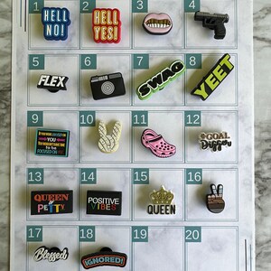 May include: A white grid with numbers 1 through 20, each square contains a different colorful charm. The charms include words like "Hell No!" and "Flex", a camera, a pair of lips, a gun, a bunny, a shoe, a crown, and a peace sign.