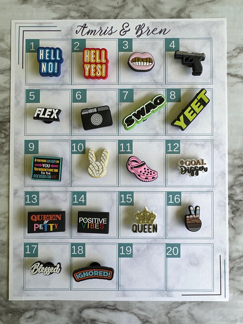 May include: A white grid with numbers 1 through 20, each square contains a different colorful charm. The charms include words like "Hell No!" and "Flex", a camera, a pair of lips, a gun, a bunny, a shoe, a crown, and a peace sign.