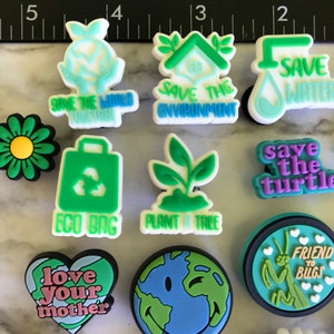 May include: A collection of 12 colorful, eco-friendly charm buttons featuring various designs, including a green eco bag, a plant, a daisy, a heart with the text "love your mother", a smiling earth, a praying mantis with the text "friend to bugs", a house with the text "save the environment", a water drop with the text "save water", a turtle with the text "save the turtle", and a hand holding a globe with the text "save the world together".