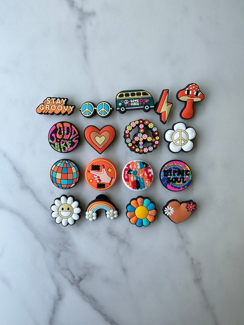 May include: A set of 16 colourful shoe charms featuring peace signs, hearts, flowers, rainbows, and other groovy designs. The charms are made of rubber and have a 70s retro vibe.