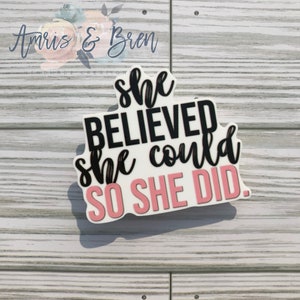 May include: White vinyl sticker with pink and black lettering. The sticker reads "She believed she could so she did."