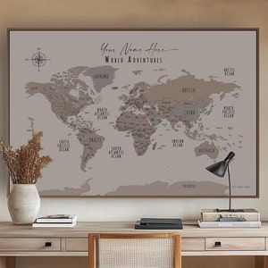 May include: A large framed world map in a home office, with the text "Your Name Here" and "World Adventures". The map is in brown and grey tones. A wooden desk and chair are positioned in front of the map. The room has a neutral colour scheme.