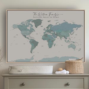 May include: A framed world map with a light grey background and teal landmasses hangs above a grey chest of drawers. The text "The Wilson Family's Adventures Around the World" is displayed. A wicker basket and a cot are also in the image.