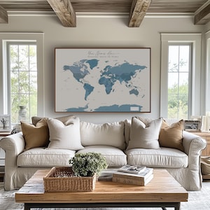Detailed calming world map in navy and dark blue as a framed canvas above a neutral-toned sofa; ideal wall art for living room spaces with a serene coastal design theme.