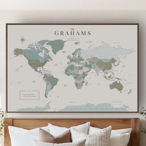 May include: A large rectangular wall map featuring a world map in muted sage green, blue, and beige tones. The text reads The GRAHAMS Adventures Around the World, with a legend for Past Adventures and Adventures to Come, framed in a dark wood border.