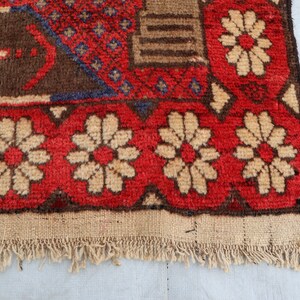 May include: Close-up of the bottom edge of a red, brown, and white patterned rug with a fringe. The rug has a floral design with white flowers on a red background.