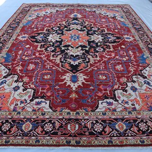 May include: A large, intricately patterned rug with a red background and a central medallion. The rug features a variety of colors, including blue, white, and orange, and has a detailed border.