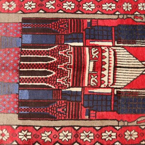 May include: A red prayer rug with a traditional Islamic design featuring a mosque and geometric patterns. The rug has a white border with floral motifs.