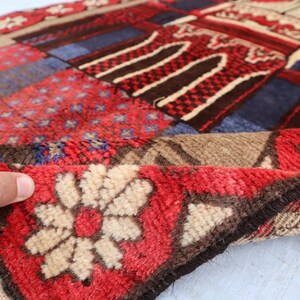 May include: A colorful patchwork rug with a red, blue, and brown geometric pattern. The rug has a fringe border and is made of soft, plush fabric.