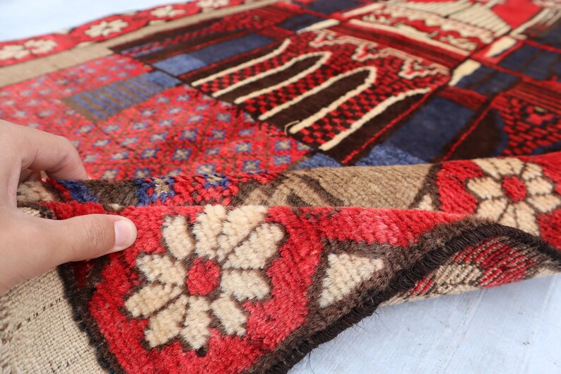 May include: A colorful patchwork rug with a red, blue, and brown geometric pattern. The rug has a fringe border and is made of soft, plush fabric.