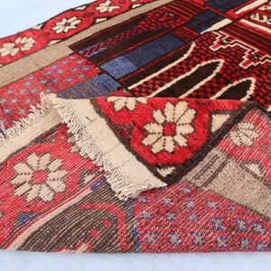 May include: A close-up of a colorful rug with a geometric pattern. The rug is made of wool and has a fringe border. The rug is folded in half, showing the different colors and patterns.