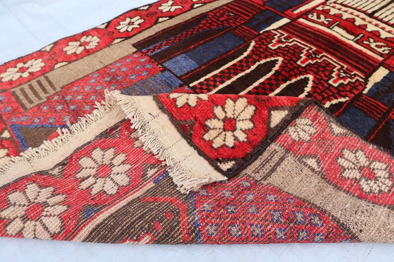 May include: A close-up of a colorful rug with a geometric pattern. The rug is made of wool and has a fringe border. The rug is folded in half, showing the different colors and patterns.
