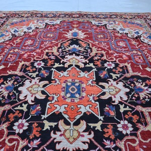 May include: A traditional Persian rug with a red, black, and cream color scheme. The rug features a central medallion with intricate floral designs and geometric patterns.