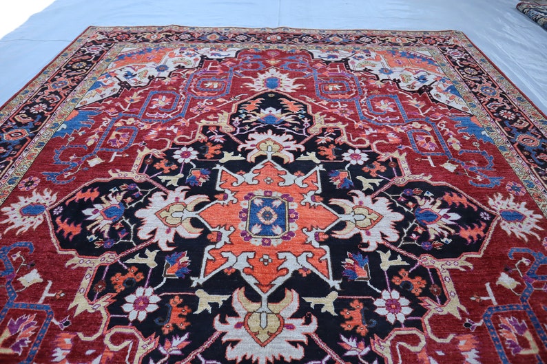May include: A traditional Persian rug with a red, black, and cream color scheme. The rug features a central medallion with intricate floral designs and geometric patterns.