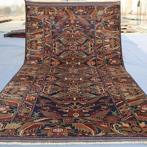 May include: A traditional Persian rug with a navy blue background and intricate floral and geometric patterns in shades of red, brown, and beige. The rug has a fringed border.