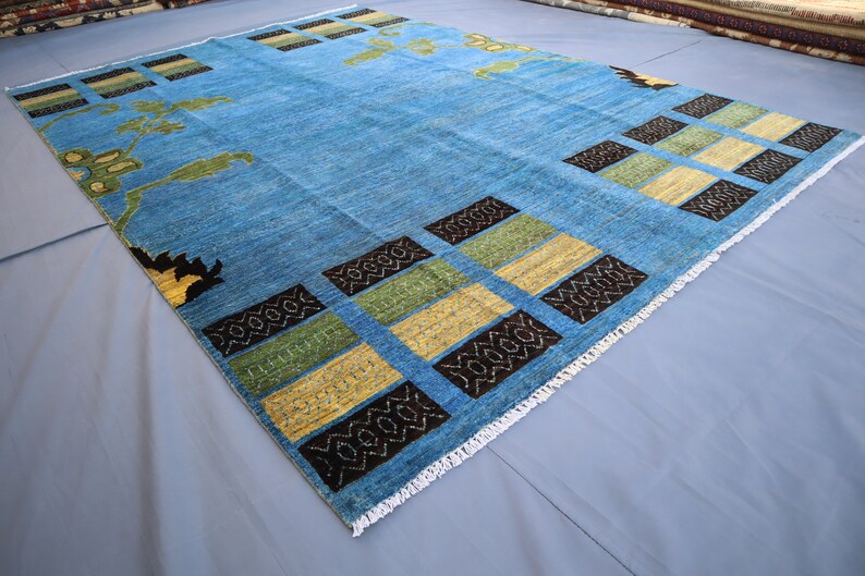 May include: A blue rug with a geometric pattern of black, yellow, and green squares. The rug has a white fringe border.