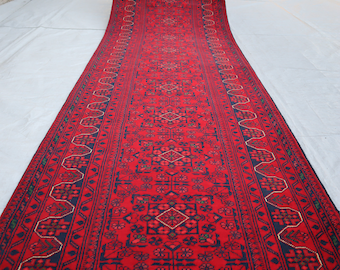 Könnte beinhalten: Ein rot-blauer Teppich mit komplizierten Mustern. Der Teppich ist auf einer weißen Oberfläche ausgerollt.