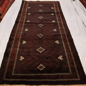 Puede incluir: Una alfombra de color rojo oscuro con un patrón geométrico en un color más claro. La alfombra tiene un borde con flecos.