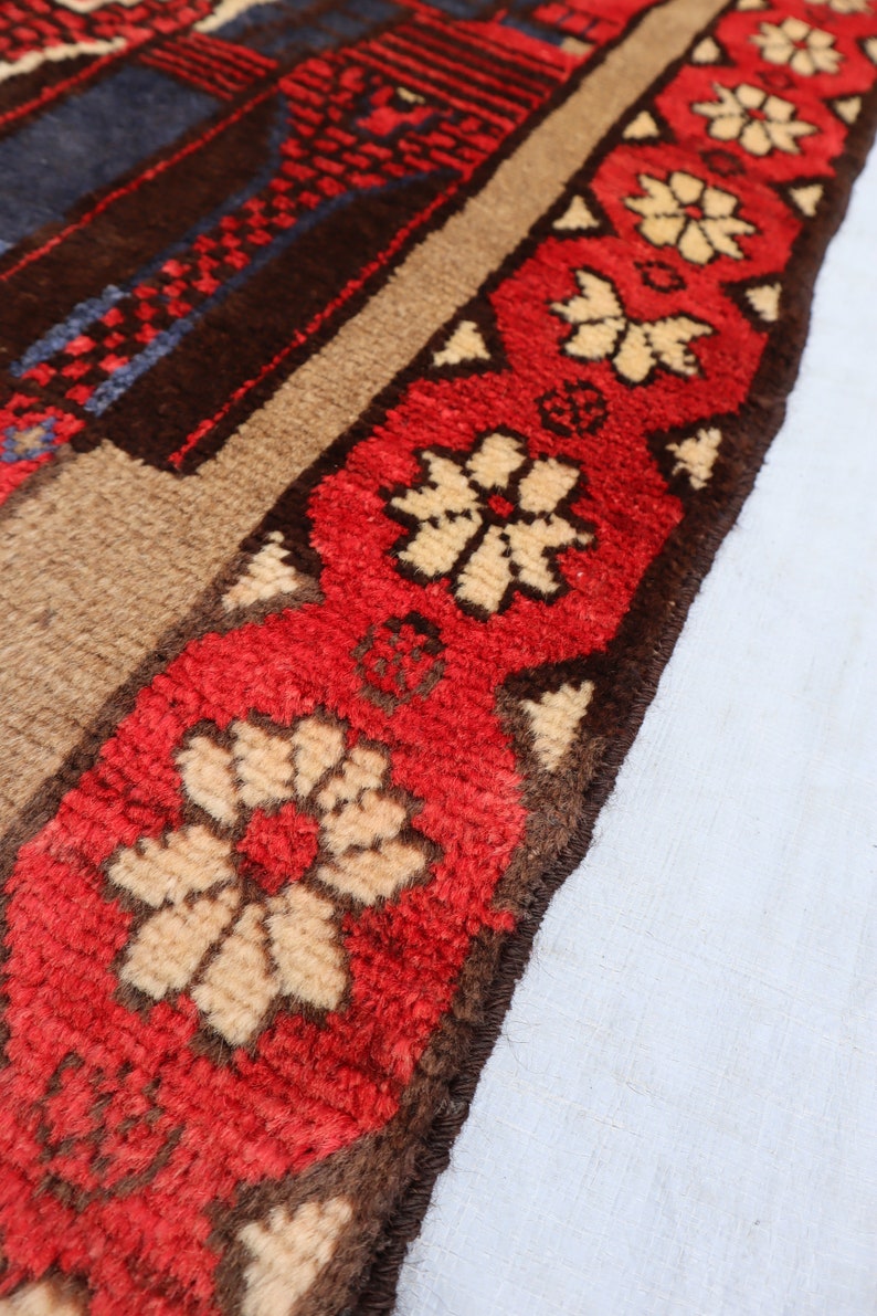 May include: Close-up of a red, brown, and cream-colored rug with a floral pattern. The rug has a fringe border.