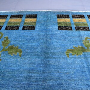 May include: A blue rug with a geometric pattern and floral designs. The rug has a light blue background with dark blue, green, and yellow accents.