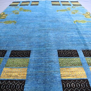 May include: A blue rug with a geometric pattern in black, green, and yellow. The rug has a floral design in the center.